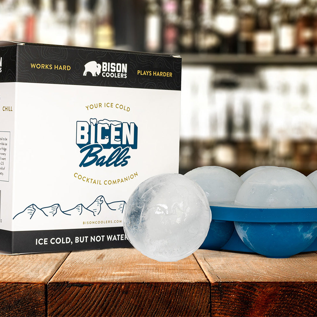 Ice ball mold by Bison Coolers, with a box on a wooden surface in front of a blurry background.